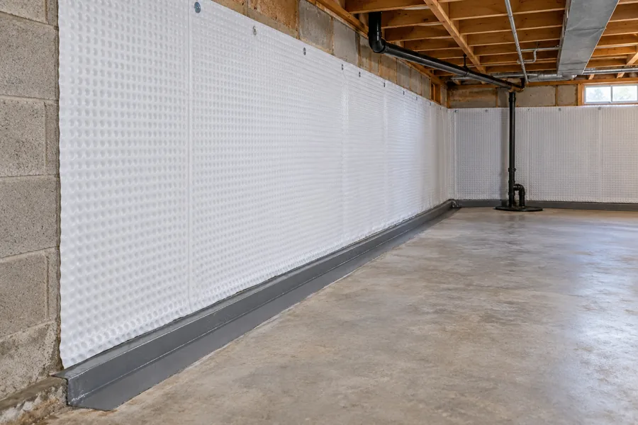 A wall drainage membrane and sealed perimeter channel in an unfinished basement.